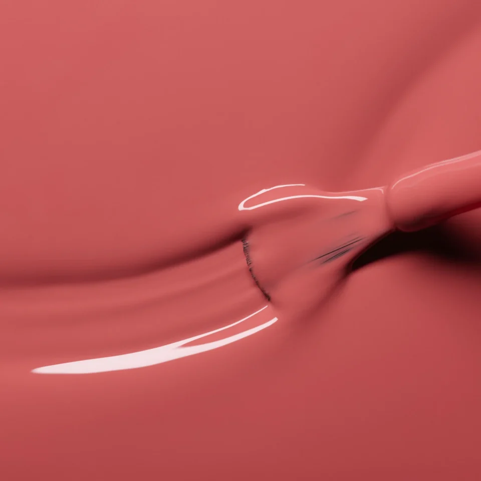 Koralinis nagų lakas tepamas ant paviršiaus stambiu planu.