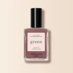 „Manucurist Green“ nagų lakas purpurinio atspalvio, pastatytas ant šviesaus fono.