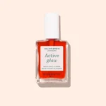 Active Glow™ Cranberry nagų stipriklis su koraliniu atspalviu, buteliukas ant šviesaus fono